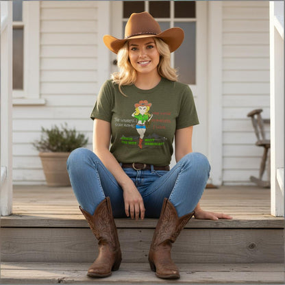 Woman wearing a green t-shirt with colorful cowgirl graphics and text, sitting on a wooden porch.