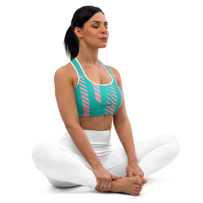 Woman wearing a green and pink sports bra and white pants on a white background