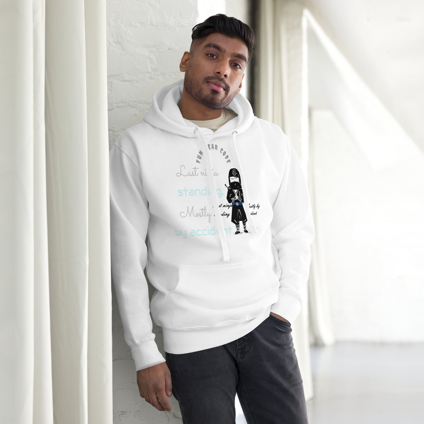 Person wearing a white hoodie with text and graphic design, standing against a light-colored wall.